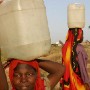 Sudanese IDP's (internally displaced people) carry 25 litres of water each on their heads filled at a water point 1km from their camp in the remote village of Muhkjar in West Darfur, Sudan Sunday 17 October 2004. Water is a serious concern for IDP's and aid organisations in Darfur who are attempting to cope with the vast numbers of IDP's and their needs in the overcrowded camps. UNICEF is providing water treatment so that it is safe to drink. The violence in Sudan's Darfur region has driven more than 1.5 million people from their homes and created what the United Nations calls one of the world's worst humanitarian crises.  