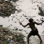 A boy retrieves a football from a polluted river in Freetown, Sierra Leone Sunday 02 April 2006. Charles Taylor the former Liberian president is locked up behind tight security and will appear before the special court in Sierra Leone Monday 03 April to make his plea against 11 counts of crimes against humanity in the impoverished nation still recovering from years of destruction during the civil war.