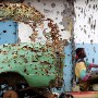 A Liberian rebel sits against a bullet riddled house and bus on the first day of a ceasefire after 14 years of civi war in Liberia 2003. Photograph © nic bothma